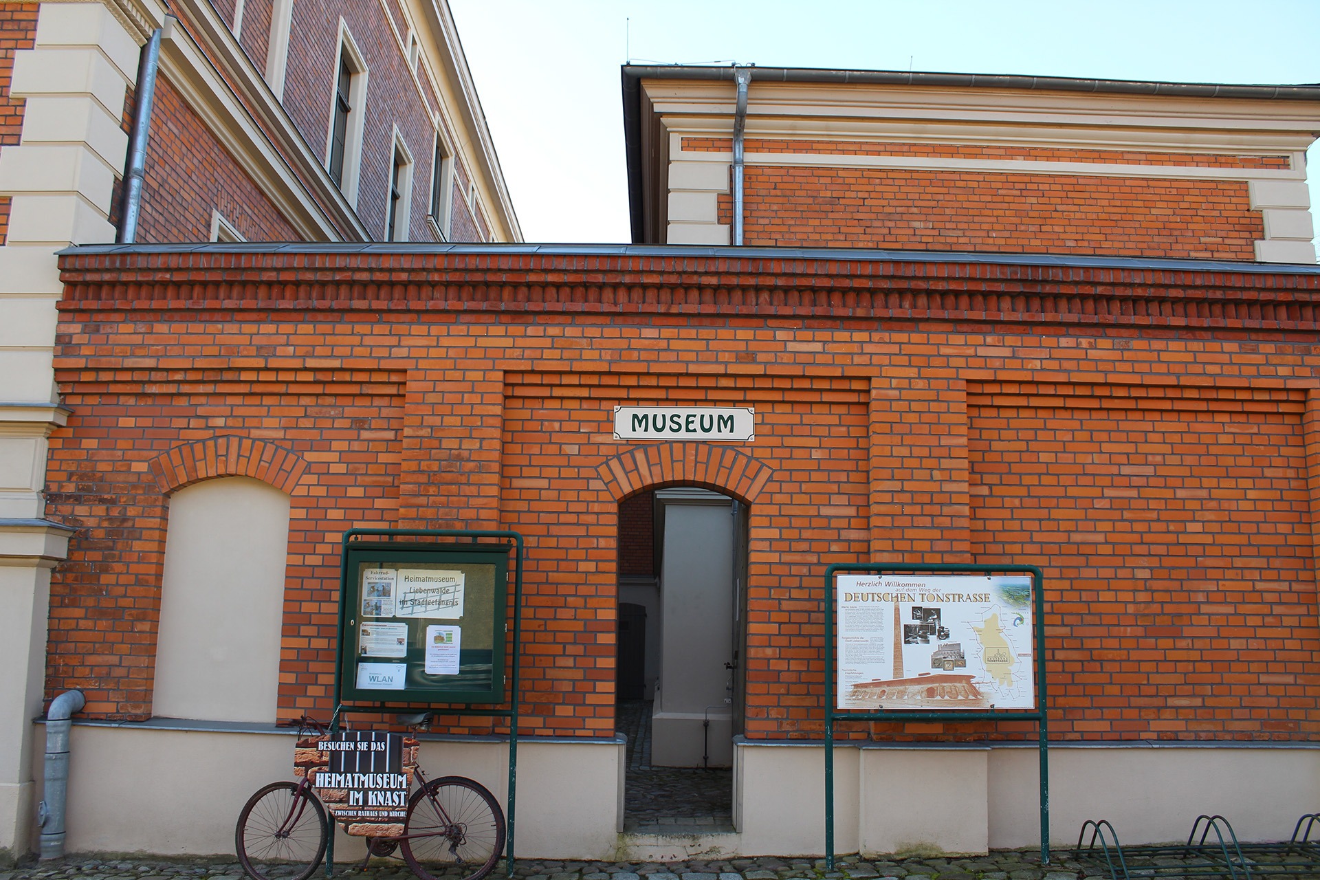 Der Eingang zum Backsteingebäude des Heimatmuseums im Knast, neben der Tür eine Informationskarte und Fahrrad mit dem Museumsnamensschild