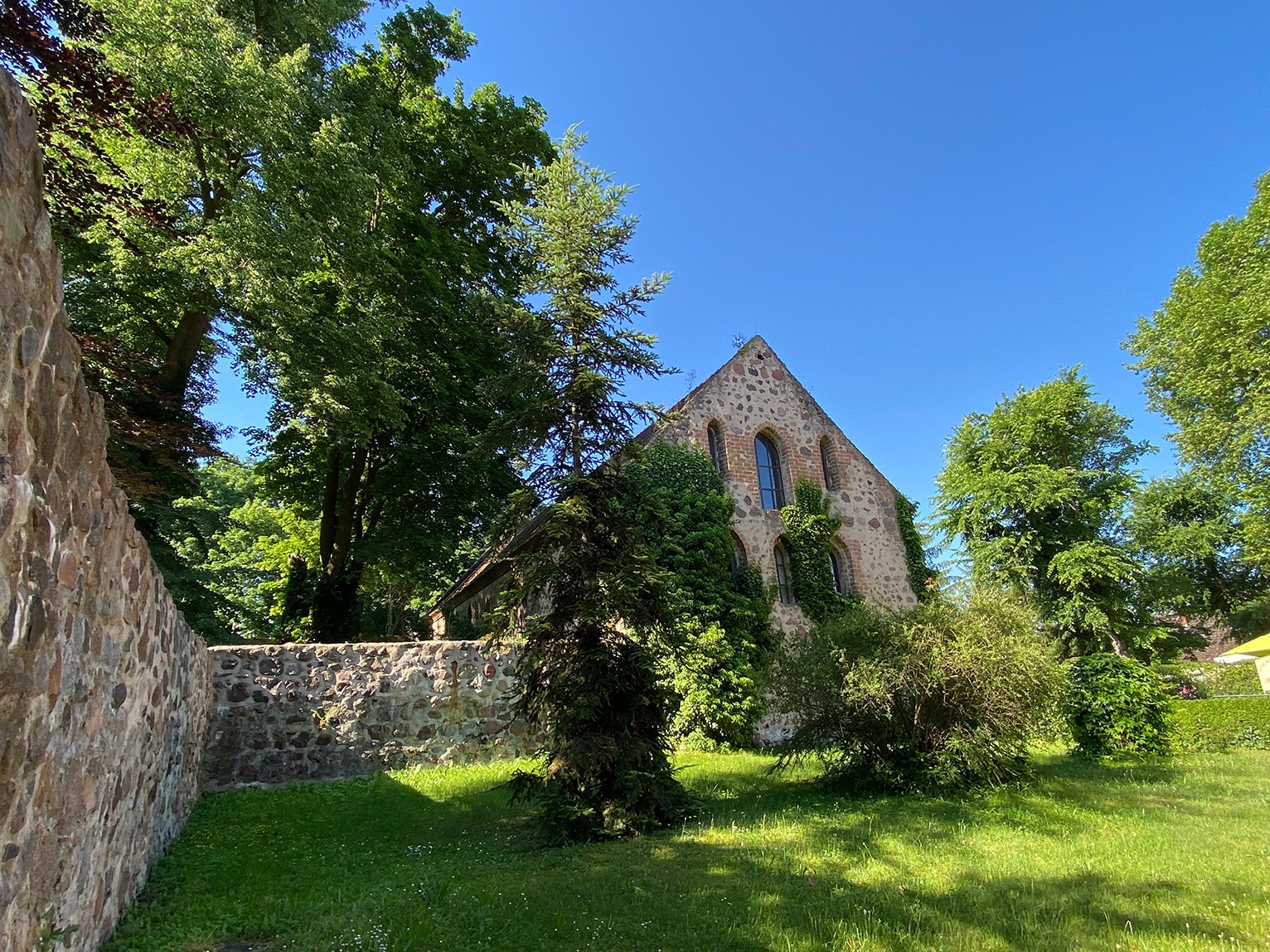 Die Klosterscheune, umgeben von üppigem Grün und einer Vielzahl von Bäumen, die eine idyllische Kulisse schaffen