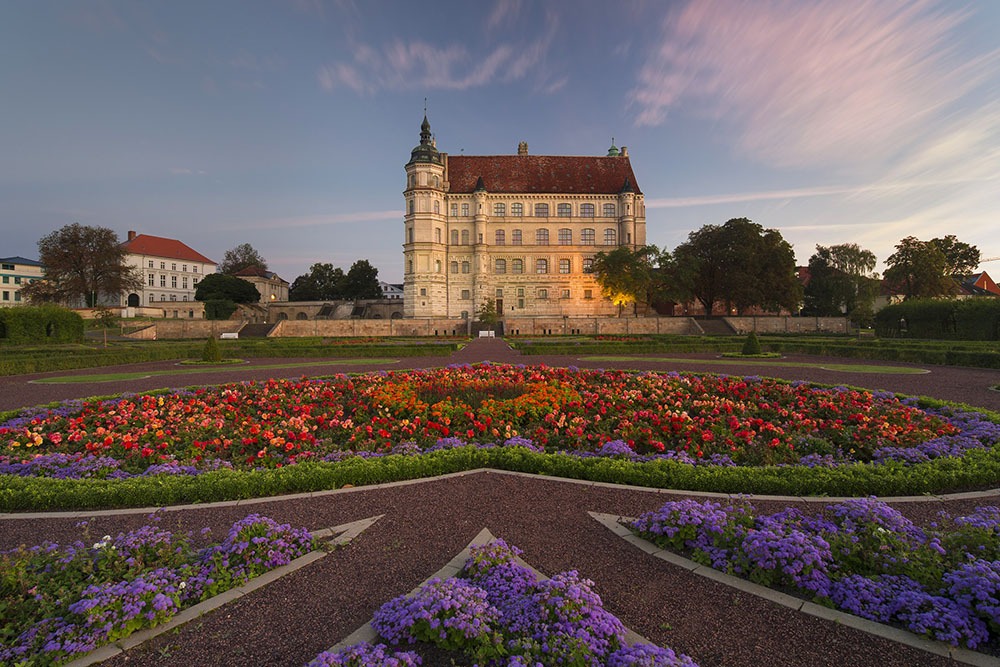 Das Schloss Güstrow im Abendrot und mit blühenden Garten erstrahlt